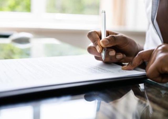 a-person-signing-a-document-with-a-pen-on-a-reflective-desk-surface a-person-signing-a-document-with-a-pen-on-a-reflective-desk-surface